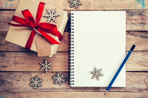 Bruine cadeau doos, sneeuwvlokken en notitieboekje op houten tafel voor Kerstmis en nieuwjaar concept.