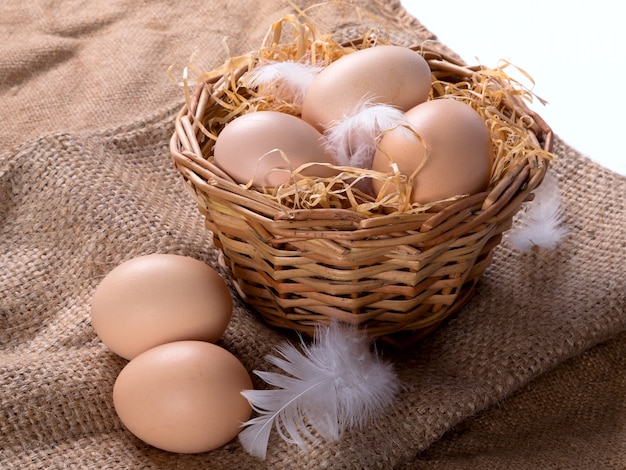 Bruine eieren in het hooi in een nest met veren. Tegen de achtergrond van jute.