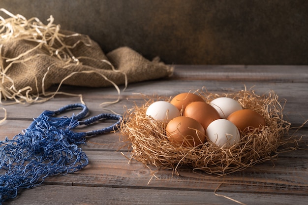 Bruine en witte kippeneieren in een nest van stro op houten achtergrond Naast eco string tas Rustieke stijl Kopieer de ruimte