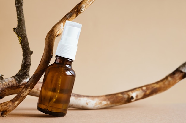 Bruine glazen fles met pomp van cosmetische producten met gedroogde takken op beige achtergrond. Natural Organic Spa Cosmetic Beauty concept Vooraanzicht zijaanzicht kopie ruimte