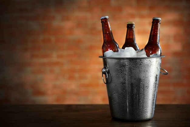 Bruine glazen flessen bier in ijsemmer op bakstenen muur achtergrond