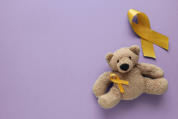 Bruine het stuk speelgoed van kinderen draagt met gele gouden linten op purpere achtergrond
