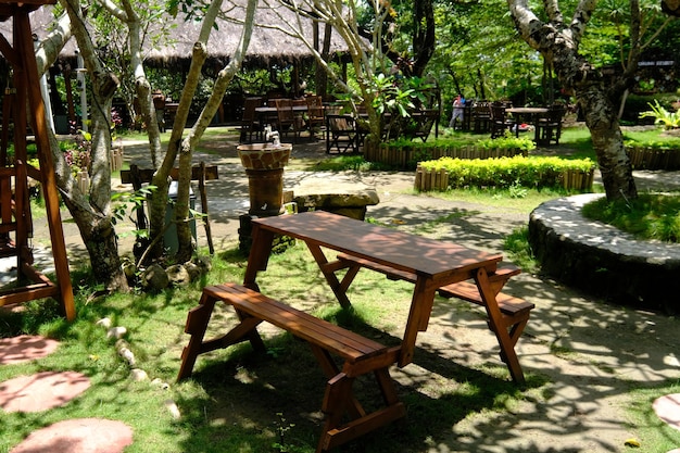 bruine houten tafel en stoelen in een schaduwrijke tropische tuin. de tuin is begroeid met groen gras.