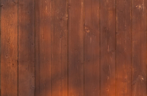 Bruine houten verticale plankomheining met verblinding door de zon.