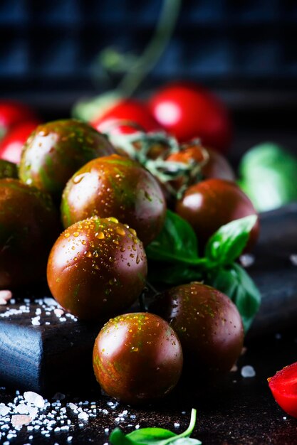 Bruine kerstomaatjes met zeezout en groene basilicum op donkere tafel herfstoogst selectieve focus