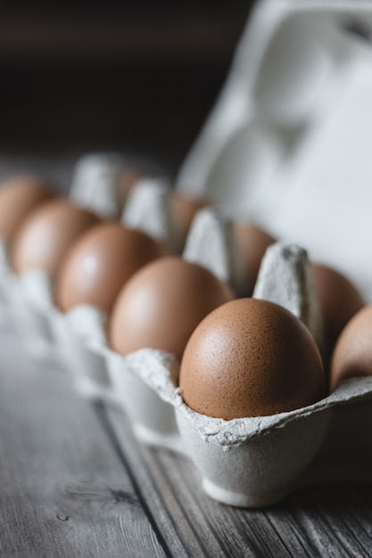 Bruine kippeneieren in een doos op houten oppervlak.