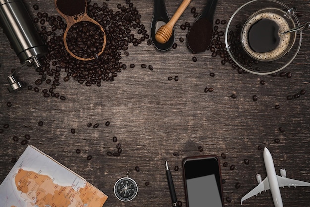 Foto bruine koffiebonen en een kop warme koffie op een houten tafel. concept reizen met kaart. tijd om te ontspannen met een kopje goede koffie. bovenaanzicht kopieerruimte voor uw tekst.