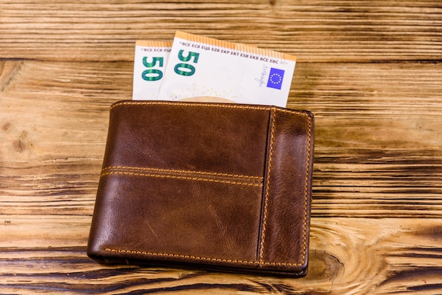 Foto bruine lederen portemonnee met vijftig eurobankbiljetten op houten achtergrond