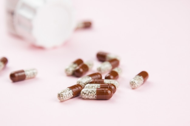 Bruine oplosbare capsules op roze. Kruidengeneesmiddelen. Alternatieve geneeskunde in capsule.