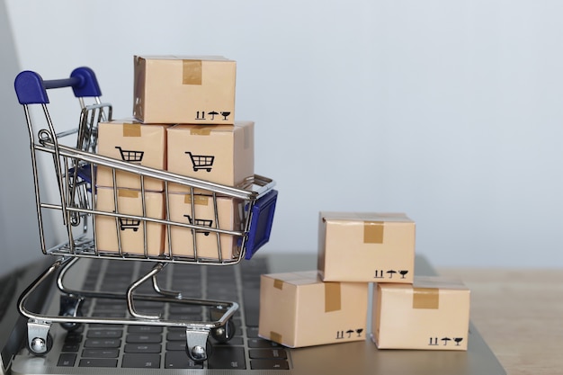 Bruine pakketdoos en Model miniatuurboodschappenwagentje op computertoetsenbord om online te winkelen
