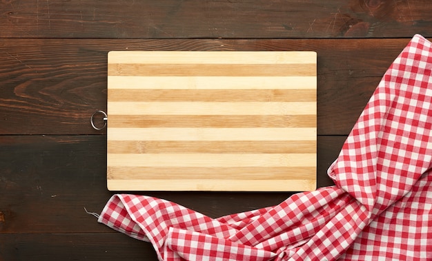 Bruine rechthoekige houten keukensnijplank en rood servet