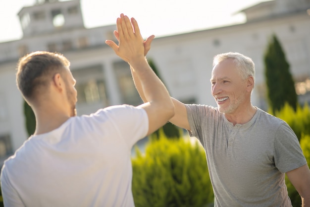 Bruinharige man en grijsharige man die high five geeft