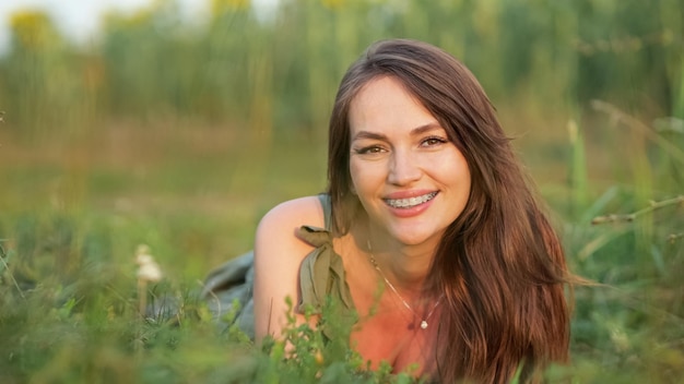 Bruinharige vrouw ligt op gras en bewondert het weidelandschap