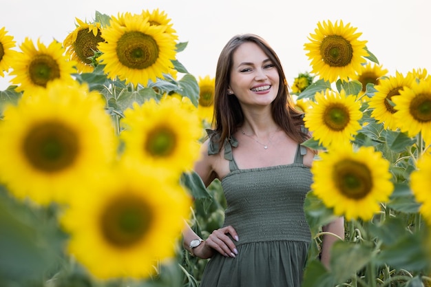 Bruinharige vrouw staat lachend tussen het zonnebloemveld