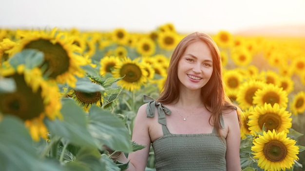 Bruinharige vrouw staat lachend tussen het zonnebloemveld