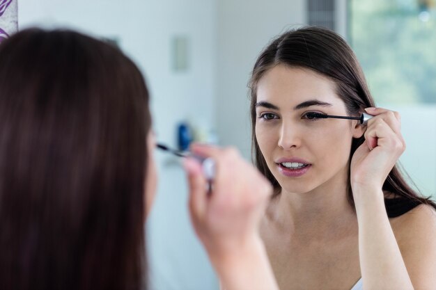 Brunette applying mascara in bathroom