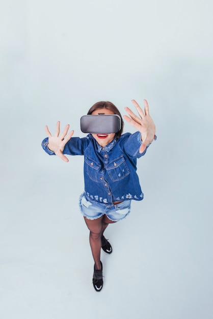 Brunette beautiful woman posing in the studio, wearing jeans wear, using VR-glasses virtual reality headsets