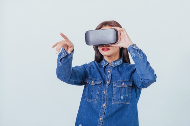 VR 안경 가상 현실 헤드셋을 사용하여 포즈, 청바지 착용을 입고 갈색 머리 아름다운 여자