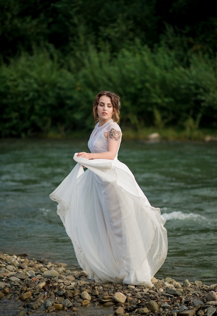 Brunette bride in beautiful wedding dress near mountain landscape.