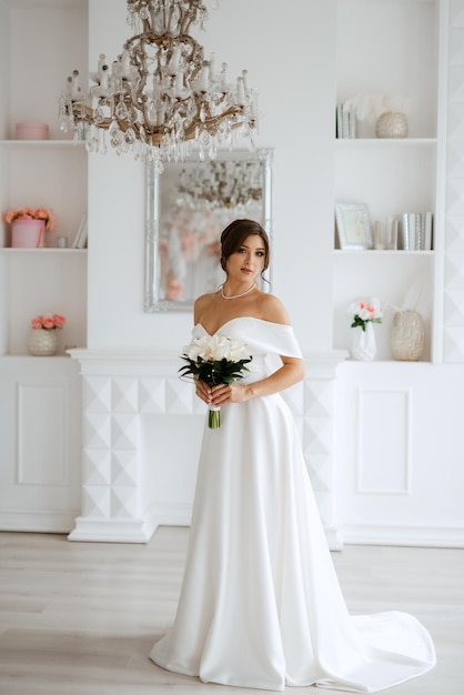 Brunette bride in a tight wedding dress in a bright studio