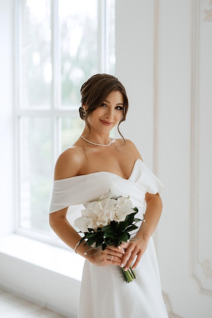 Brunette bride in a tight wedding dress in a bright studio