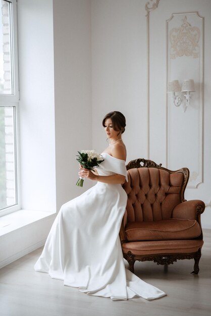 Brunette bride in a tight wedding dress in a bright studio