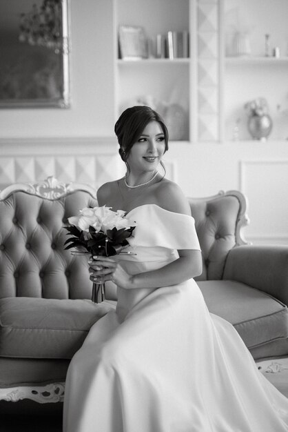 Photo brunette bride in a tight wedding dress in a bright studio