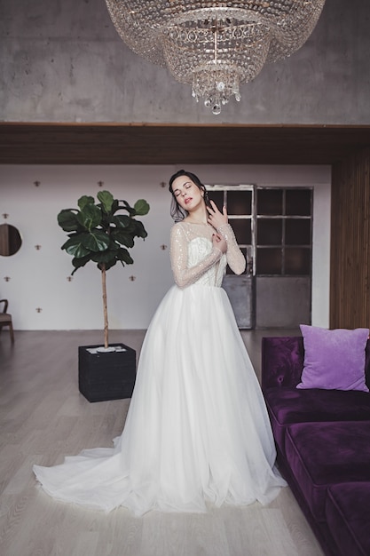 Brunette bride with makeup in a wedding dress in a luxurious interior