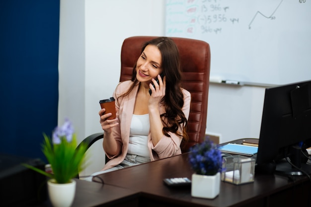 Donna castana di affari che chiacchiera sullo smartphone