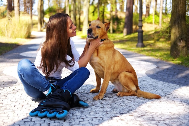 Brunette casual female having fun with her brown pitbull dog in a park.