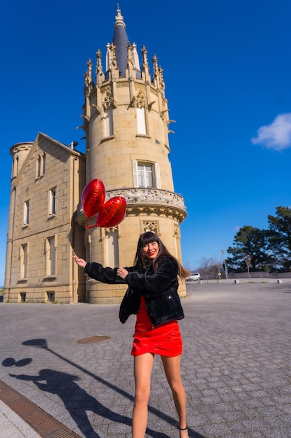 Брюнетка кавказская девушка влюблена в сердечные шарики в день святого валентина, гуляя с ними в день празднования