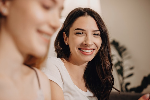 Foto la donna caucasica castana sta sorridendo mentre guarda il suo amico di zenzero e seduto sul divano