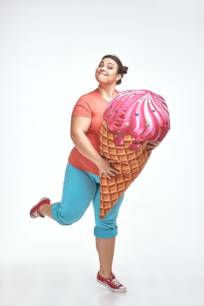 Brunette chubby woman is holding a huge ice cream