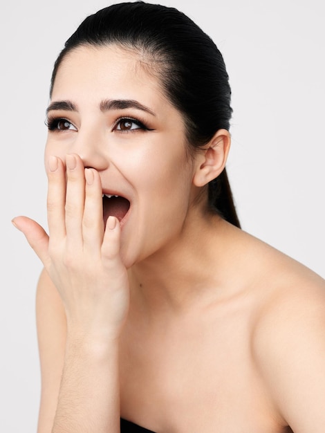 Brunette covering her face with her hand bare shoulders closeup