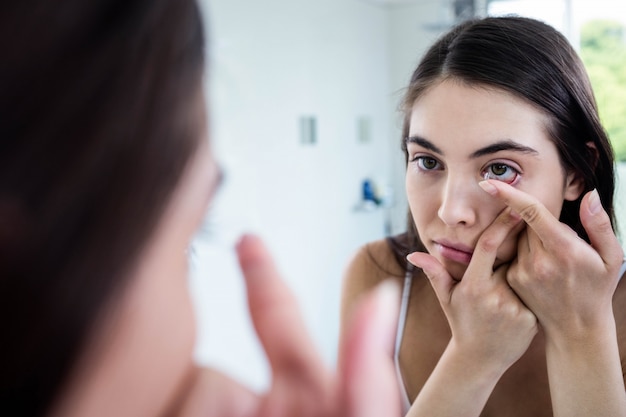 Brunette die haar contactlens in badkamers zet