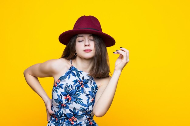 Brunette in a dress and hat dancing on a yellow background