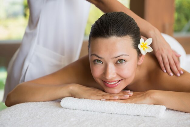 Brunette enjoying a peaceful massage smiling at camera