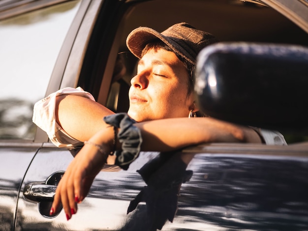 Brunette female in a black car under the sunlight