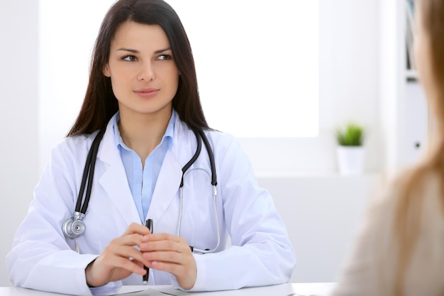 Brunette female doctor talking to patient in the hospital.