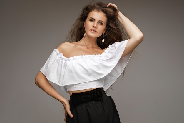 Brunette female wearing white blouse and black skirt giving her head a scratch