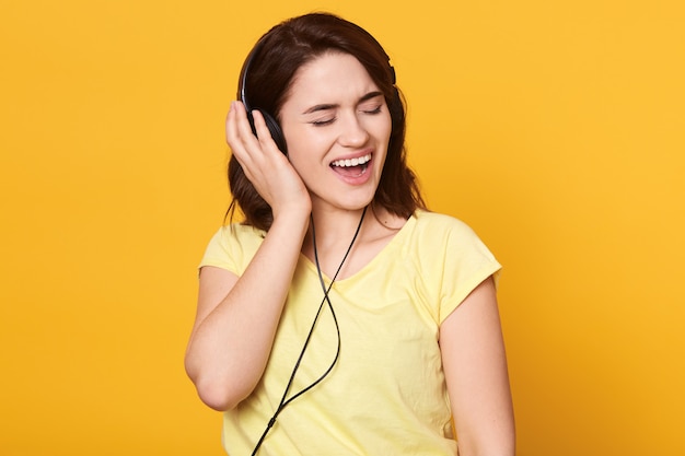 Brunette female with headphones listening to favorite music and singing