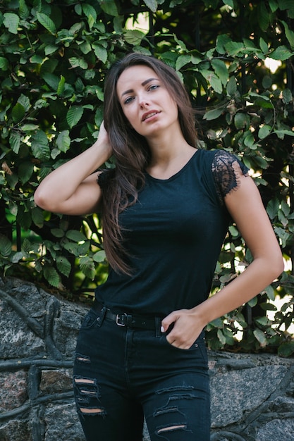 A brunette female with long hair wearing a blank black t-shirt