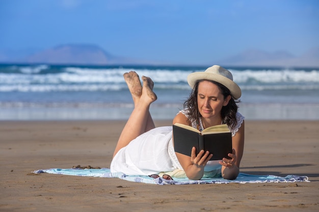 Brunette geniet van lezen in de buurt van golvende zee