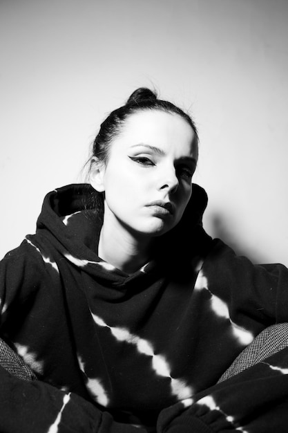 Photo brunette girl in a black hoodie light background high quality photo