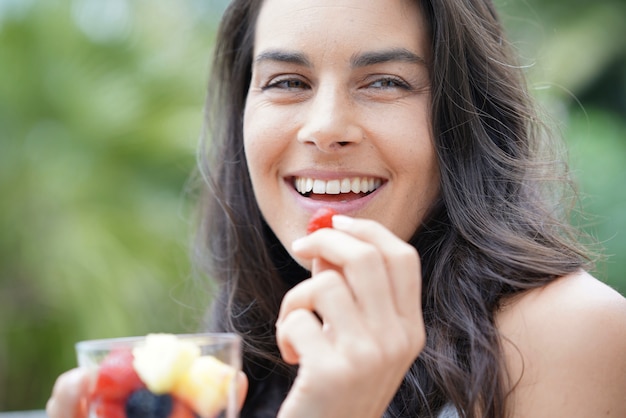 Brunette girl eating fresh fruits