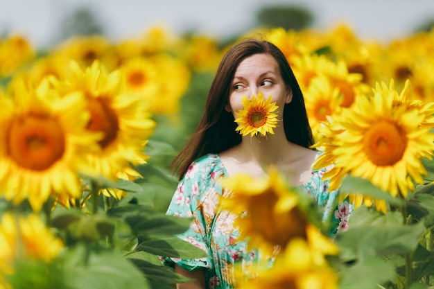 La ragazza bruna in un campo di girasoli