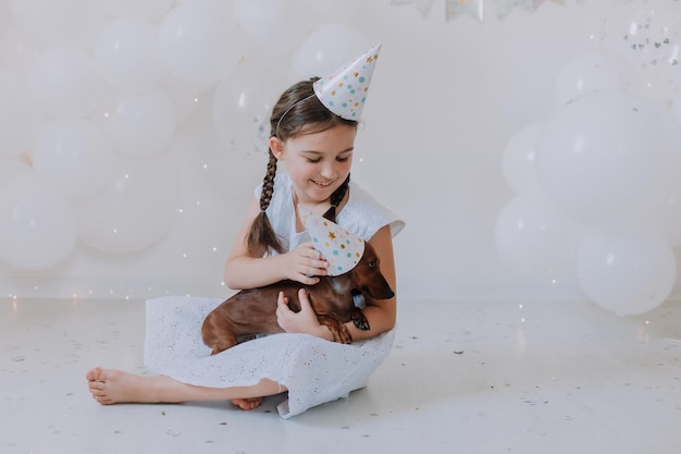 brunette girl and her favorite dog dachshund in festive hats lie on the floor in front of the camera