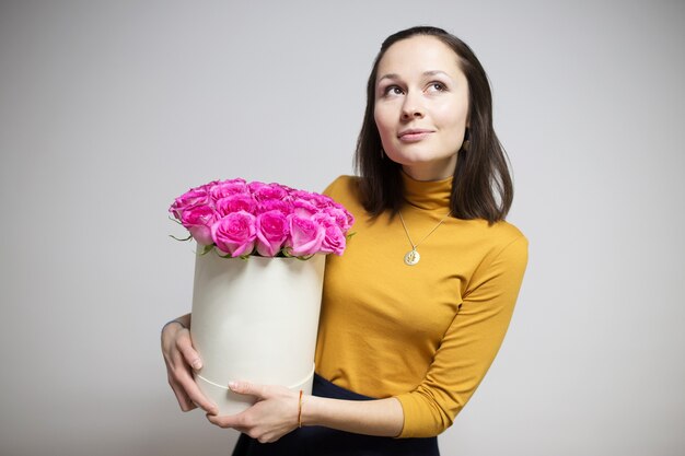 写真 ボックスに明るいピンクのバラの花束を保持しているブルネットの少女