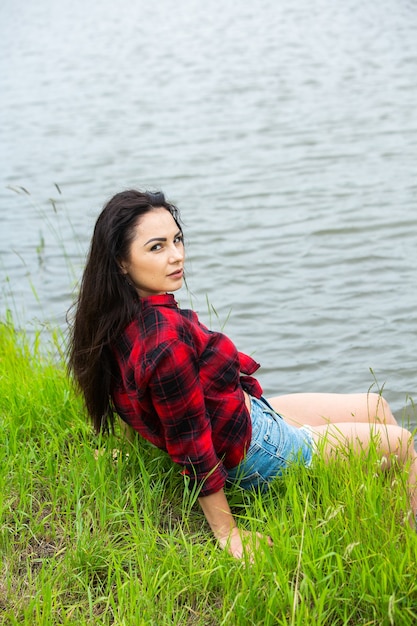 The brunette girl is having fun in the river in rubber boots in the country Young woman on a lake enjoy the life