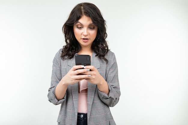 Brunette girl is surfing the internet holding a phone in her hands